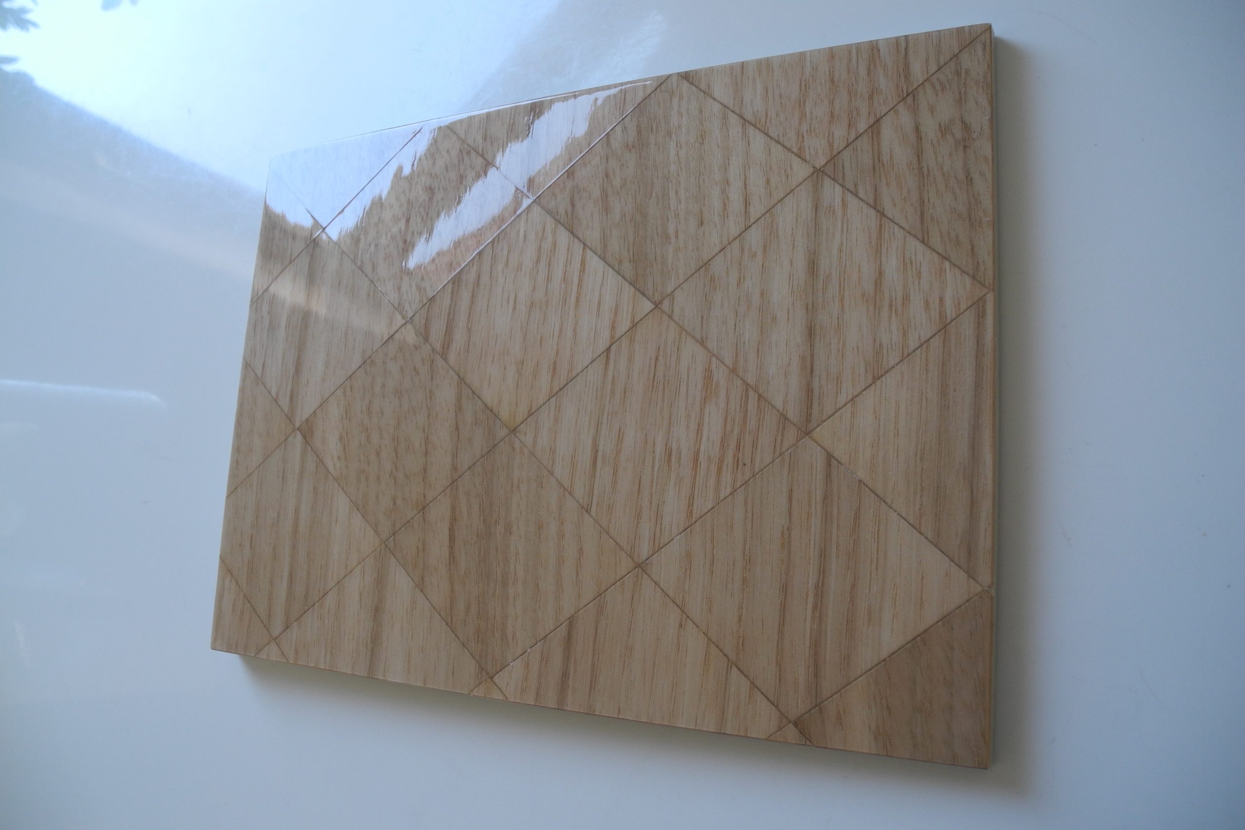 Probefläche eines Holzfurniers mit Rautendesign und glänzendem Lack.