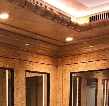 Ecke eines komplett mit Holzfurnier ausgelegtem Raumes. In die Wände sind Spiegel eingelassen.